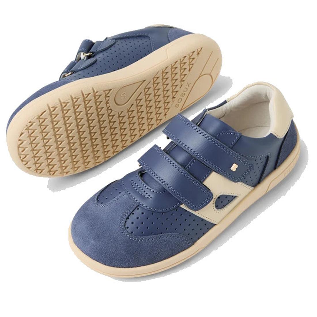 The Bobux KP Kids Plus Titan Juniors Leather Sneaker in Vintage Indigo Blue features adjustable straps, perforated detailing, and a durable beige rubber sole. One shoe is upright; the other lies on its side to show the tread pattern., 9420074855824, 94200