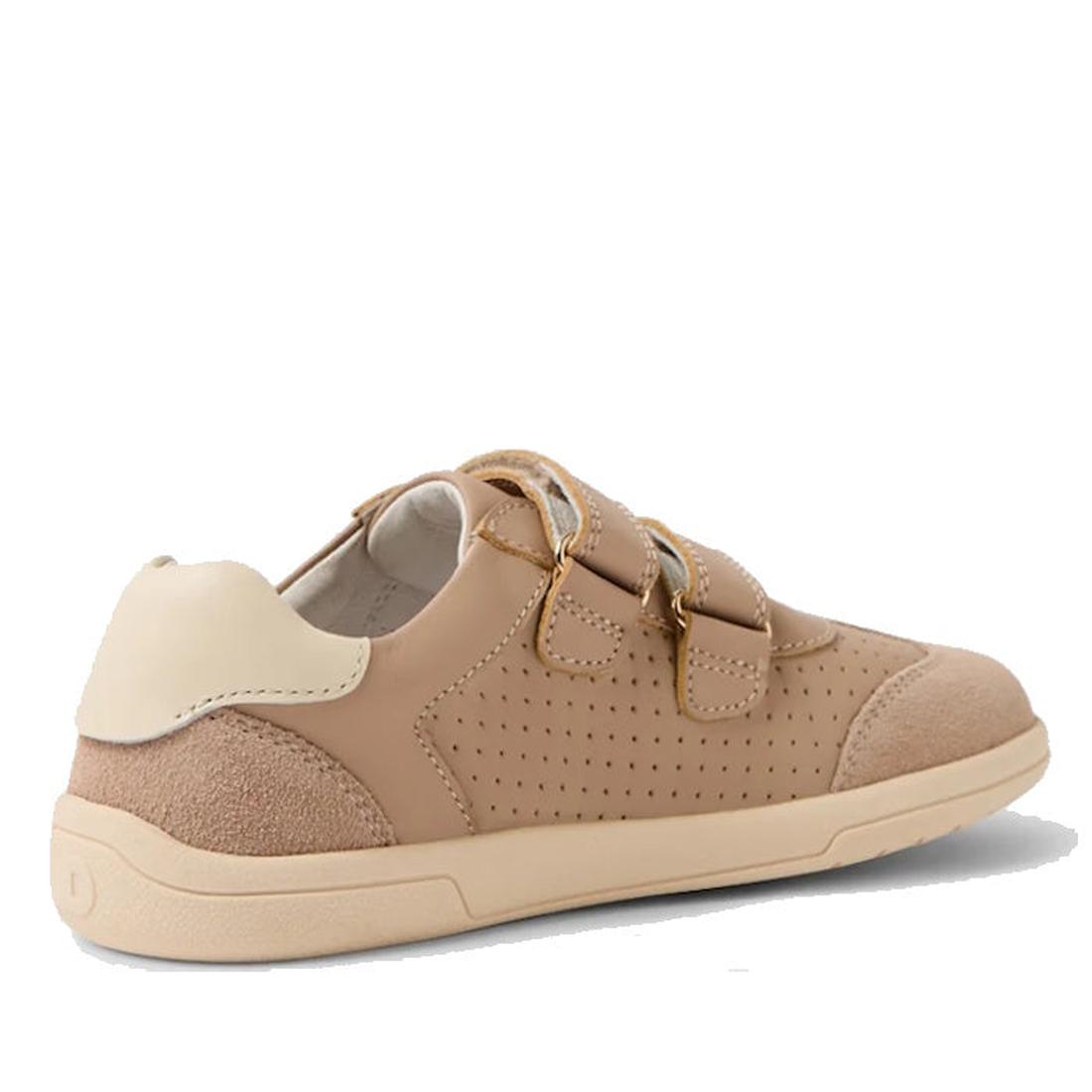 The Bobux KP Kids Plus Titan Juniors Leather Sneaker in Warm Taupe features a beige leather design with a cream heel, adjustable hook-and-loop straps, perforated side panel, and a light beige slip-resistant sole—shown from the side and back., 942007485589