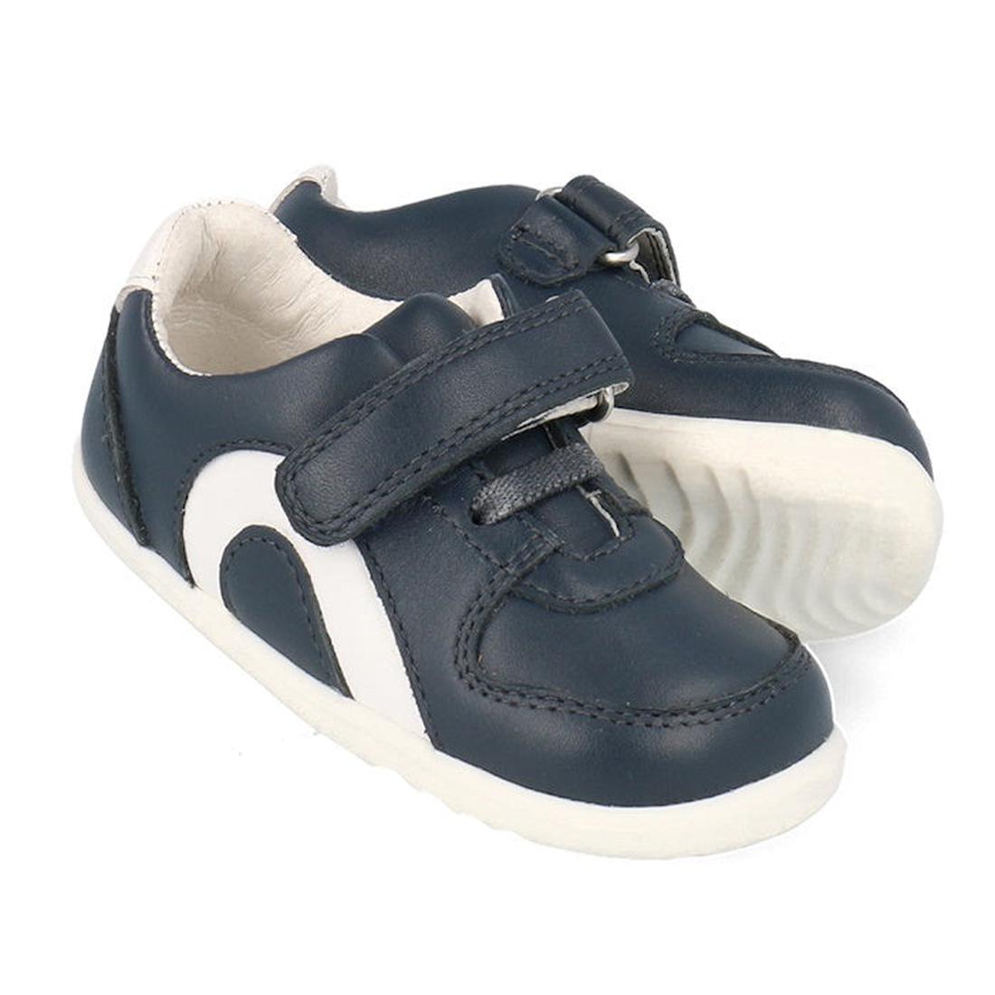 The Bobux Step Up SU Toddlers Leather Sneaker Comet Navy 734603 is a navy kids sneaker with white soles, side accents, hook-and-loop strap, elastic laces for easy fastening, and a flexible sole for comfort.