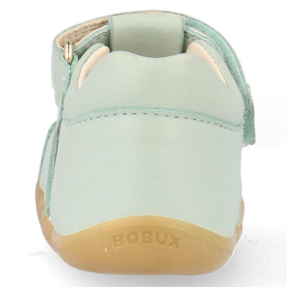 A close-up rear view of the Bobux Step Ups Compass Mist Aqua 734905 toddler girls sandal in light green leather with a tan rubber sole, featuring the BOBUX name embossed on the back—highlighting this stylish first walker., 9420075708594, 9420075708600, 94