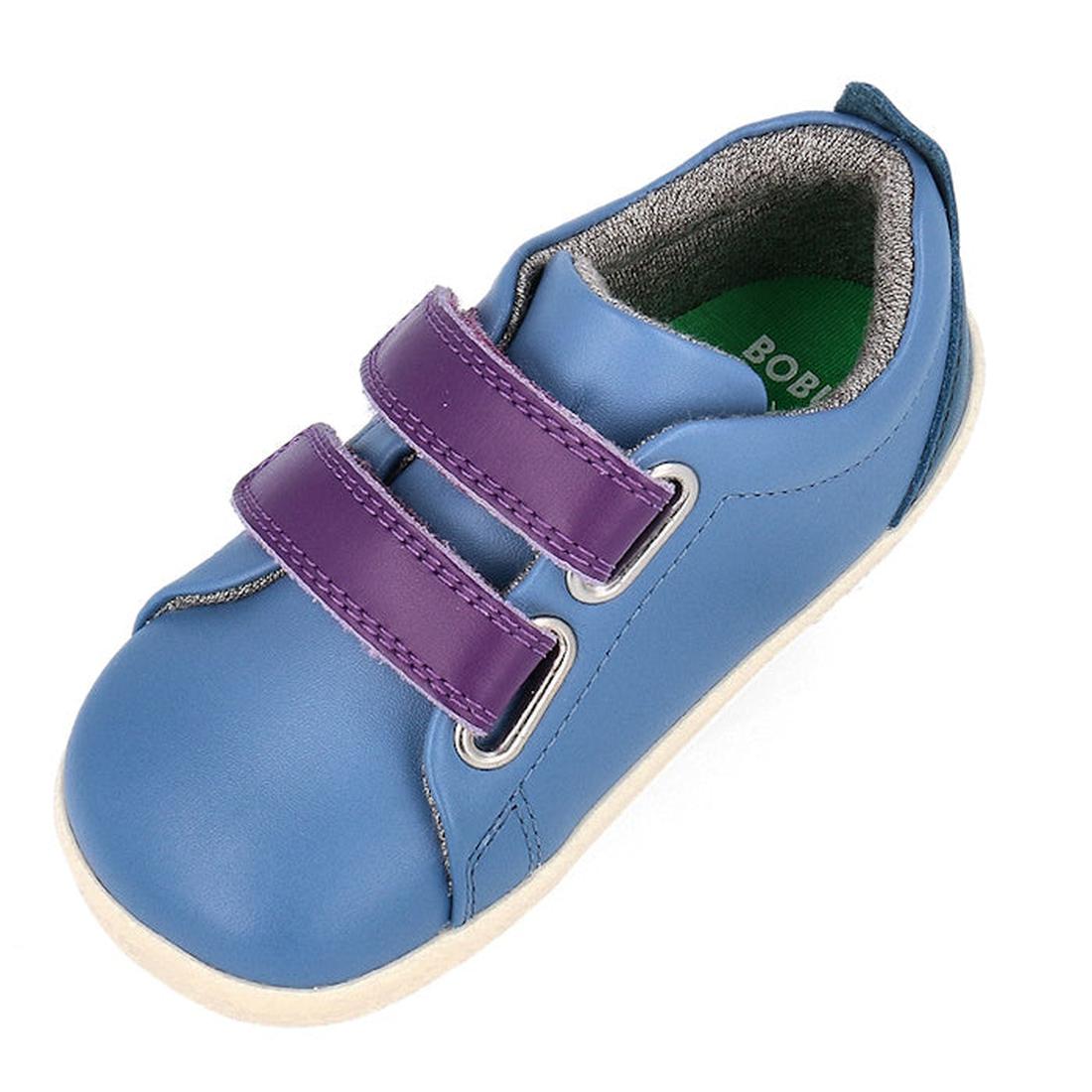 The Bobux Step Up Grass Court Trainer in Elemental Blue (734205) is a toddler shoe with a leather upper, two purple Velcro straps, green insole, gray interior lining, and white sole, viewed from an overhead angle., 9420075773202, 9420075768741, 9420075771