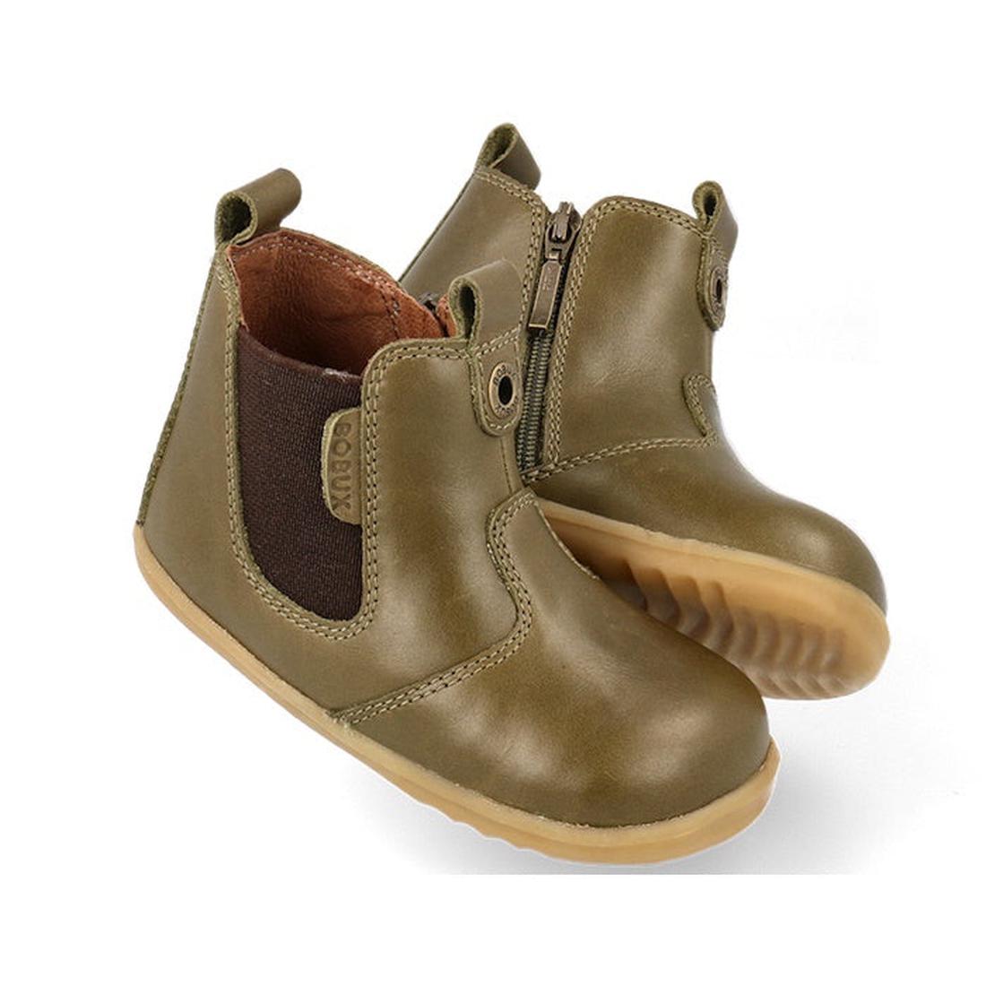 The Bobux Step Up Jodphur Boot Olive 721960 is an olive green unisex toddler ankle boot with leather upper, side zipper, brown elastic panels, pull tabs, and tan rubber soles—ideal first walkers shown on a white background.