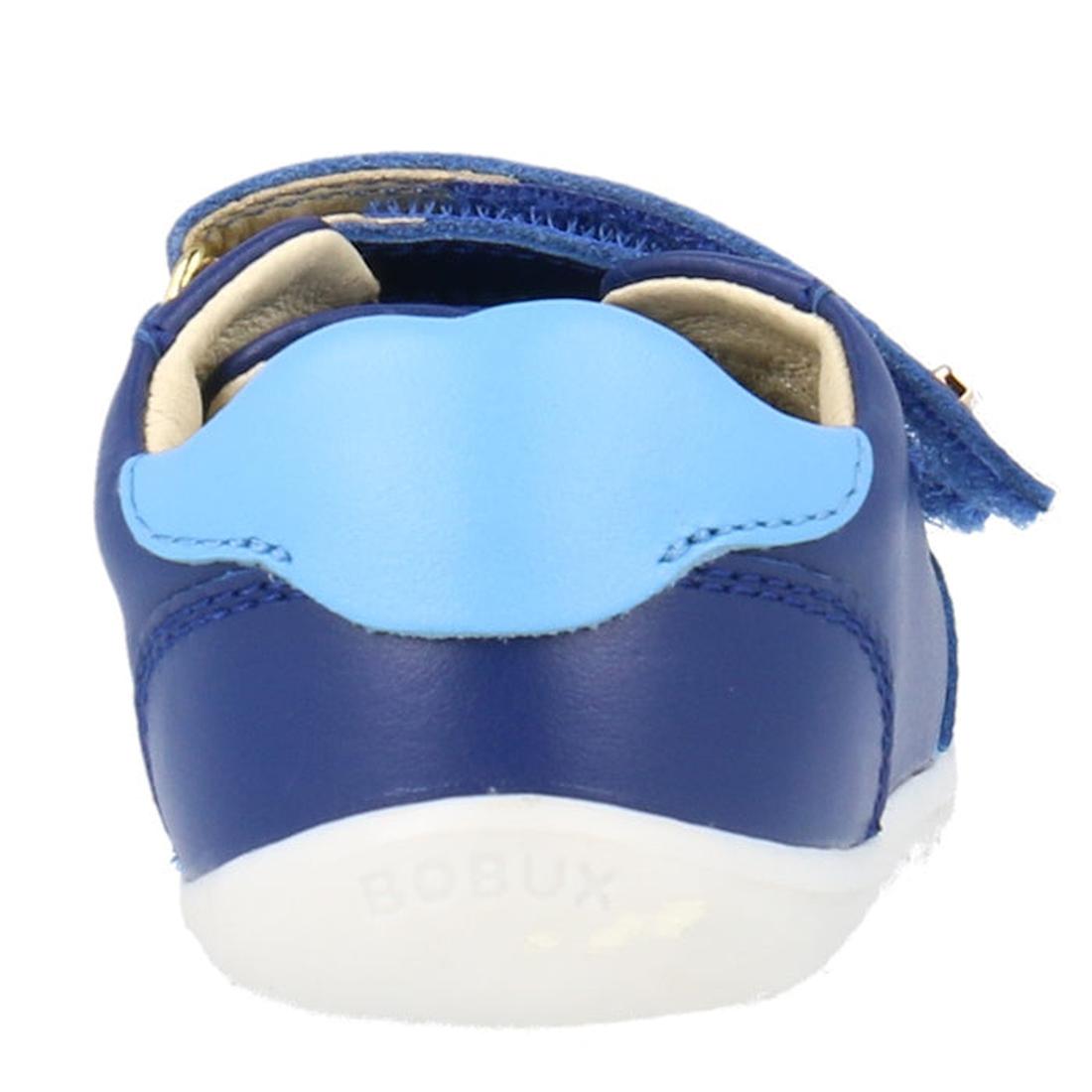 A close-up rear view of the Bobux Step Up SU Riley Sneaker in Blueberry shows its unisex style, light blue heel accent, white sole, and open double strap closures with the BOBUX logo faintly visible., 9420075794962, 9420075794863, 9420075795112, 942007579