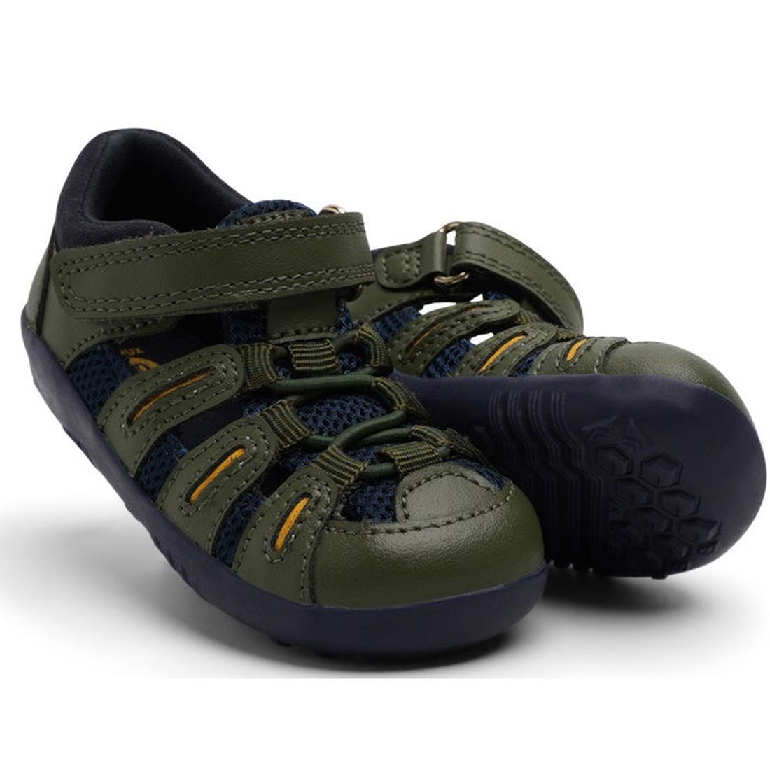 The Bobux Step Up Toddlers Summit Forest Green Navy Sandal 731610 features green and navy mesh, black soles, and yellow accents; one sandal stands upright while the other tilts to show its textured sole—ideal for adventurous toddlers.