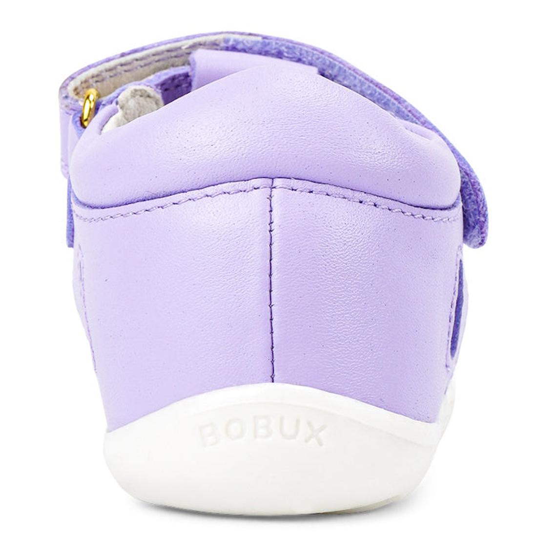 A close-up rear view of the Bobux Step Up Tropicana II Lilac Toddler Girls Sandal shows its light purple Quick Dry leather with a white sole embossed BOBUX, featuring a closed toe and purple strap with gold detail for all-day comfort., 9420071314096, 9420