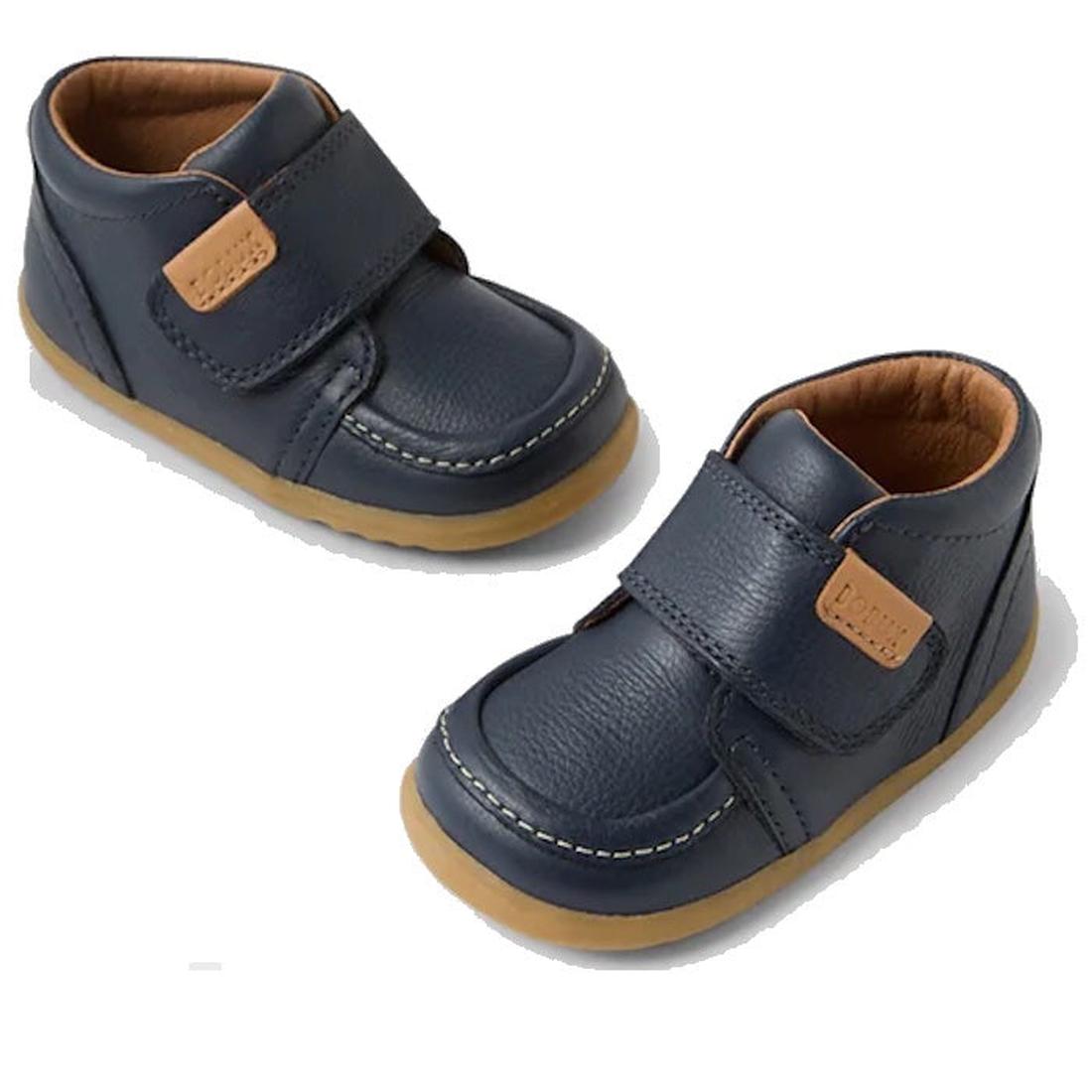 The Bobux IW Iwalk Grover Toddlers Navy Leather Boot features navy leather, tan soles, brown inner lining, visible stitching, an adjustable Velcro strap with a small tan patch for easy fastening.