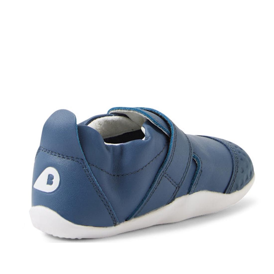 The Bobux XP Xplorer First Walking Shoes Go Vintage Indigo Blue features a blue leather upper, flexible white sole, velcro strap, and white B logo on the heel—perfect for little ones starting to walk. Shown from the back and side angles., 9420074842657, 9