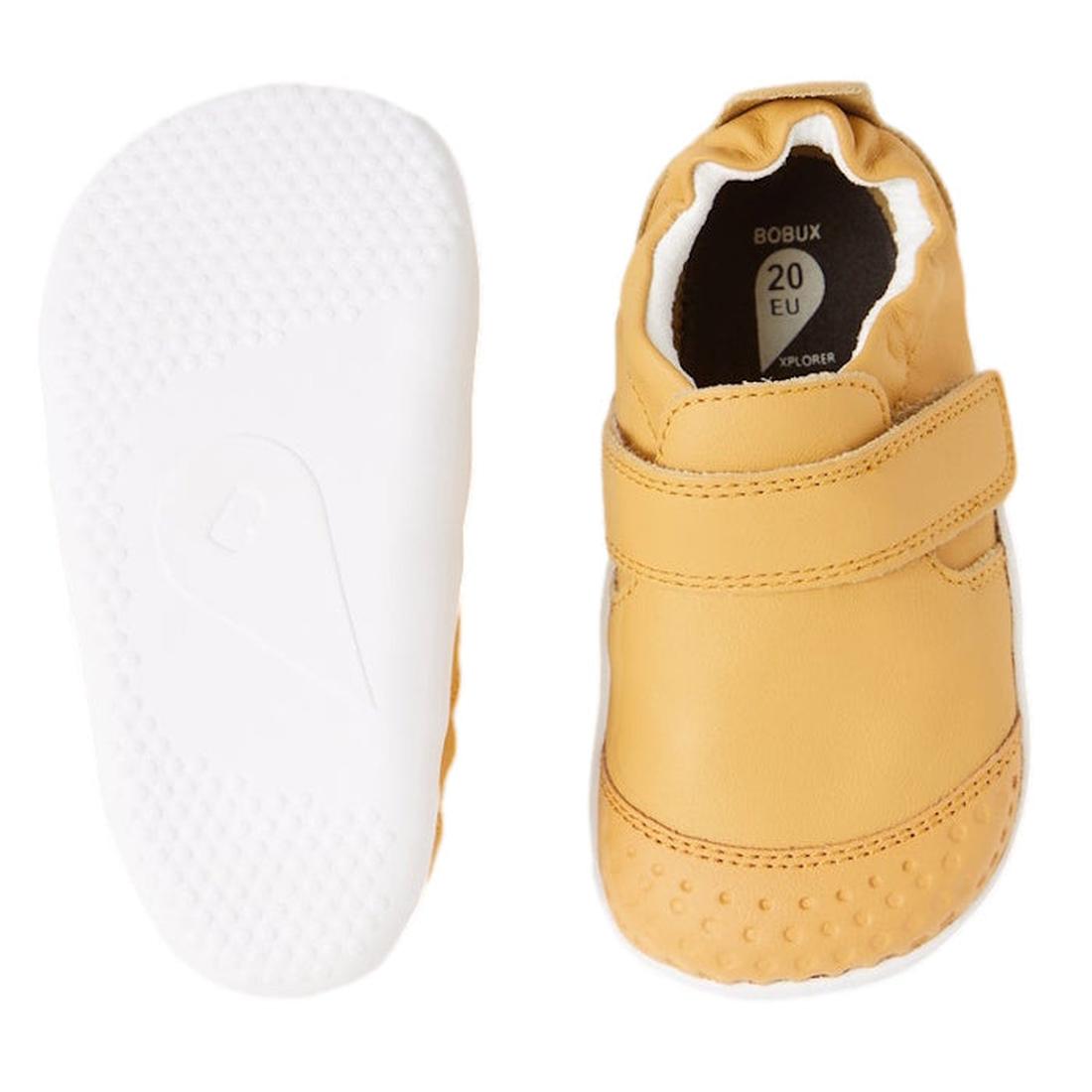 The Bobux XP Xplorer First Walking Shoes Go Oak Buff Tan are pre-walker leather shoes for first steps, shown from the side and sole. One displays a white flexible sole, the other features a velcro strap and soft, rounded toe., 9420068567962, 9420068567979