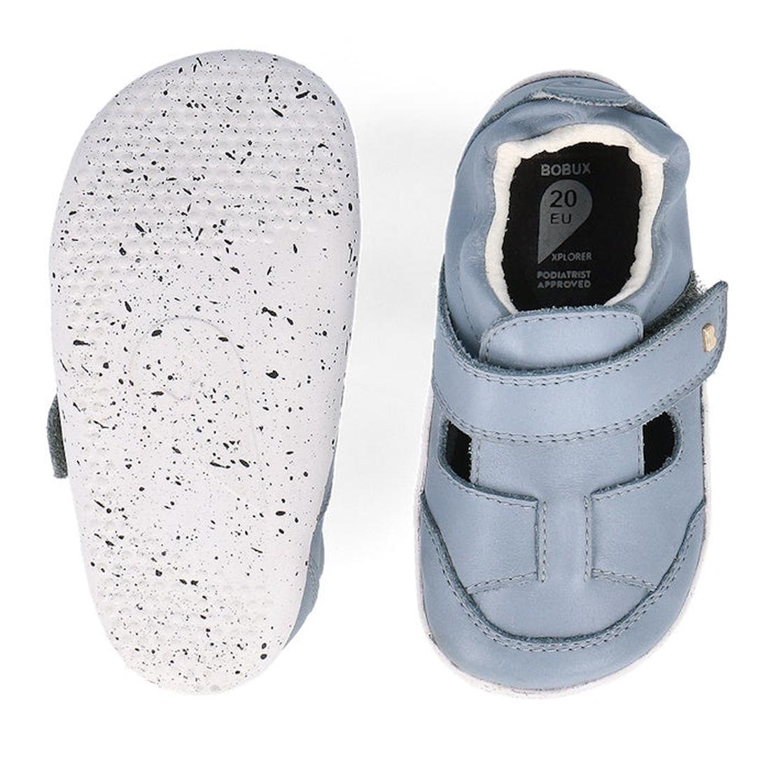 The Bobux XP Explorer Beau First Walker Sandal 502303 features light blue toddler shoes with white, speckled flexible soles; one shoe is shown from the top, the other from the bottom showing tread and size label—ideal for first steps., 9420075784628, 9420