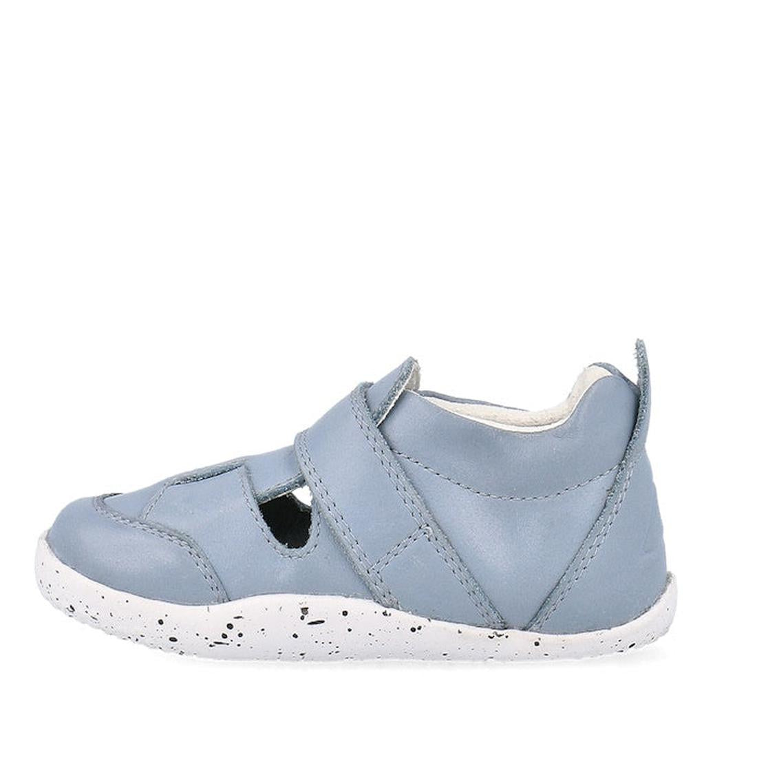 The Bobux XP Explorer Beau First Walker Sandal 502303 is a light blue closed-toe toddler shoe with cut-out sides, a white speckled flexible sole, and a hook-and-loop strap for easy fastening—perfect for learning to walk., 9420075784628, 9420075784994, 942