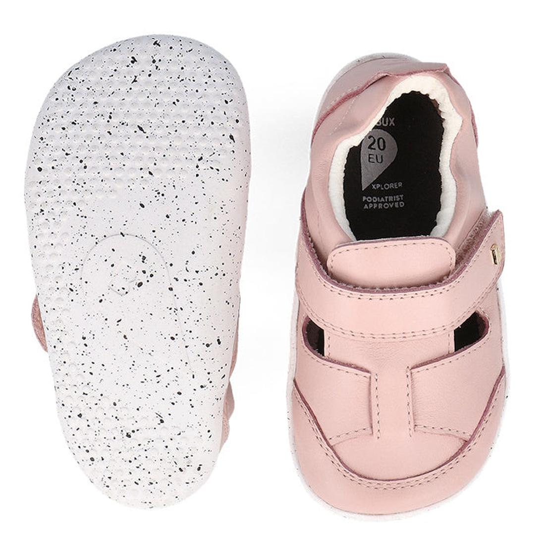 The Bobux XP Explorer Beau First Walker Sandal in Blossom Pink features white, textured flexible soles with black speckles. One shoe is shown from the top with a velcro strap; the other displays its sole., 9420075785915, 9420075784284, 9420075783980, 9420