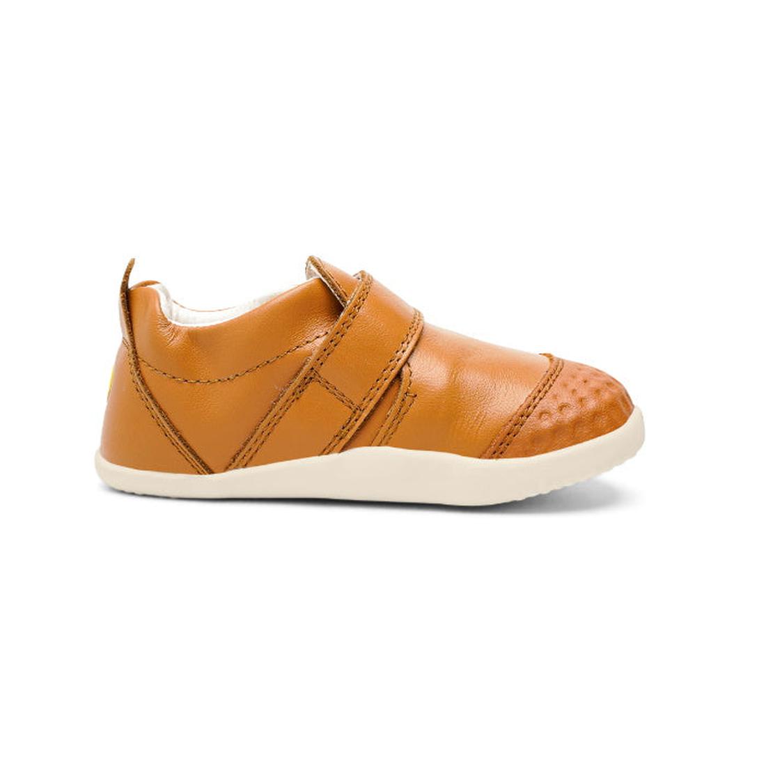 The Bobux Xplorer Go Caramel Tan First Walker 501037 is a small, soft leather baby shoe in brown with a flexible sole and Velcro strap, ideal for first steps, shown in profile on a white background., 9420071319039, 9420071319046, 9420071319053, 9420071319