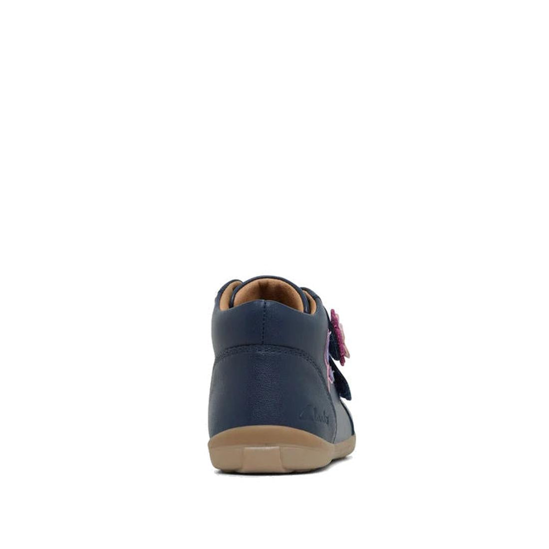 The Clarks Kids Manuela Leather Boot in navy is shown from the back, featuring a beige sole and a pink flower detail on the side. This comfortable kids boot stands centered against a plain white background., 36288, 9336078980168, 9336078980182, 9336078980