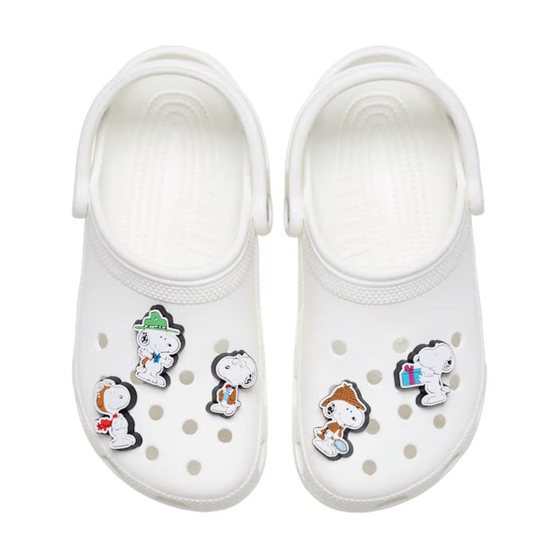 A pair of white slip-on clogs styled with the Crocs Jibbitz 5 Pack - Peanuts Snoopy, featuring fun Snoopy-themed cartoon charms attached to the holes on top of the shoes., 196265356751