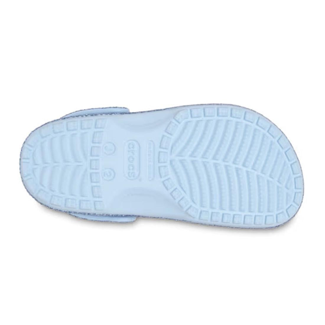 A light blue Crocs Kids - Classic Chunky Glitter Clogs, shown from the bottom, reveals a textured sole with tread patterns and the brand name embossed in the center—ideal for kids' shoe collections., 198445287688, 198445287695, 198445287701, 198445287718,