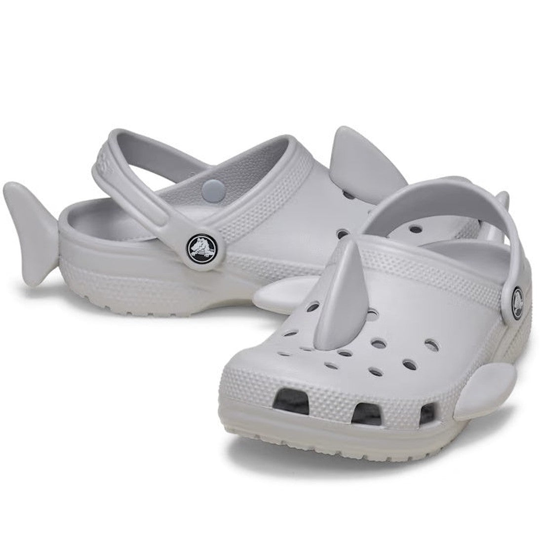Crocs Kids I Am Shark Clog Youths in grey are playful slip-on clogs with fun shark fins, tails, secure heel straps, and comfy soles.  ksnz