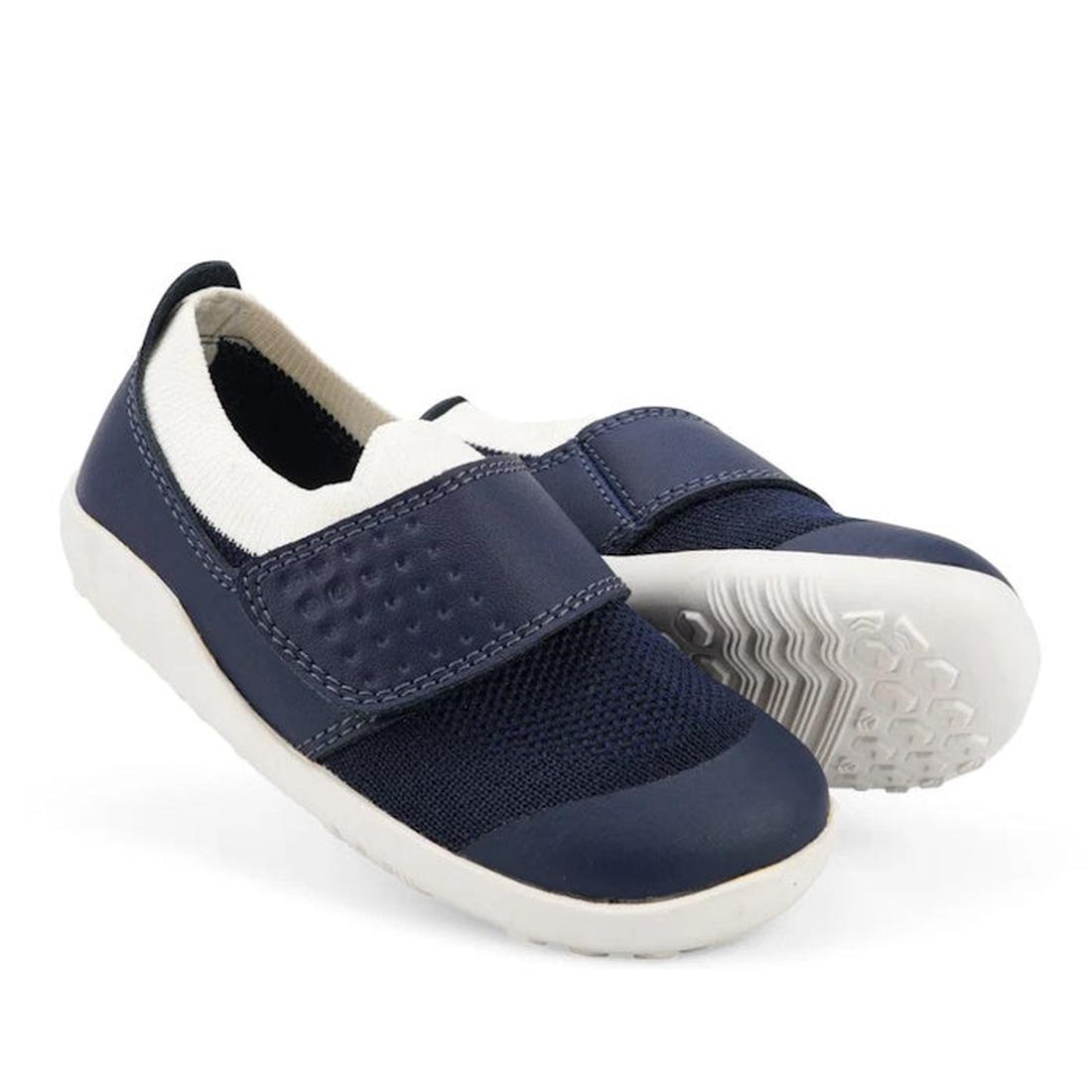 A pair of Bobux Kid+ Lo Dimension III Navy 838610 kids shoes on clearance, featuring white soles, Velcro straps, and a white ankle collar; one shoe stands upright while the other shows its textured sole., 9420068533202, 9420068533219, 9420068533226, 94200