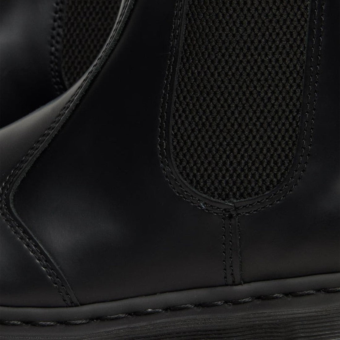 Close-up of Dr. Martens 2976 Mono Black Chelsea Boot in smooth leather, showcasing detailed stitching, textured elastic side panel, and thick rubber sole—classic features of this iconic black mono style., 22760, 190665314717, 190665314724, 190665314731, 1
