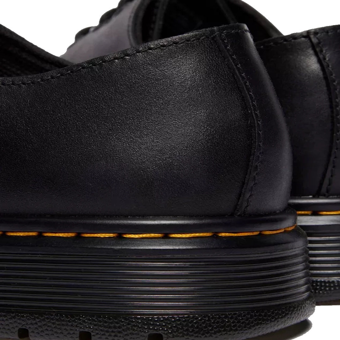 Close-up of the Dr Martens Brookline Dark Black Lusso Leather Shoe, showing thick ribbed soles, visible yellow stitching, and lightweight black leather construction.