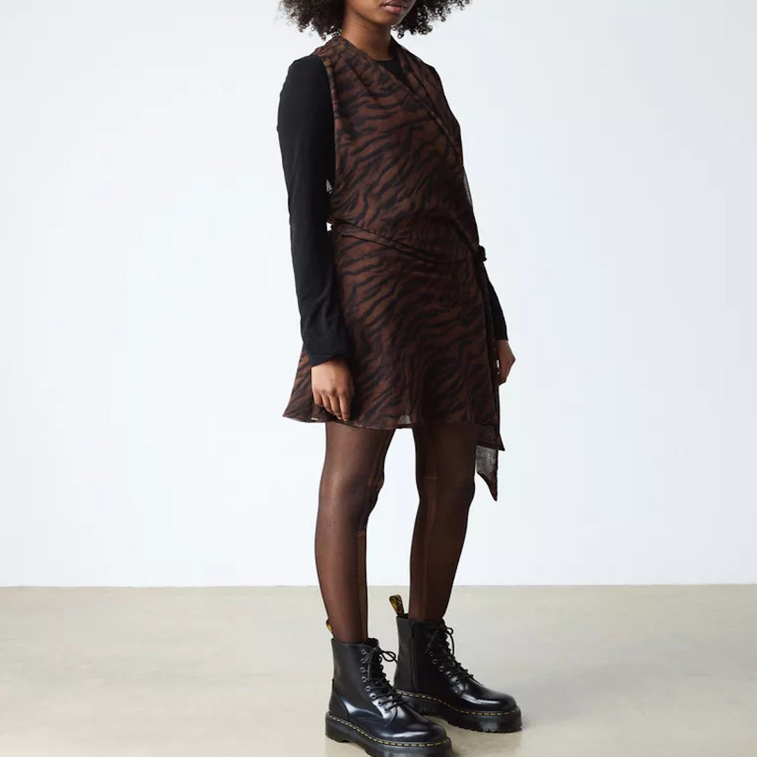 A person stands against a plain background wearing a brown and black animal print dress, black long-sleeve shirt, sheer tights, and Dr Martens - Jadon Polished Smooth Boot 8 up for an edgy look., 883985578883, 883985578890, 883985578906, 883985578913, 883
