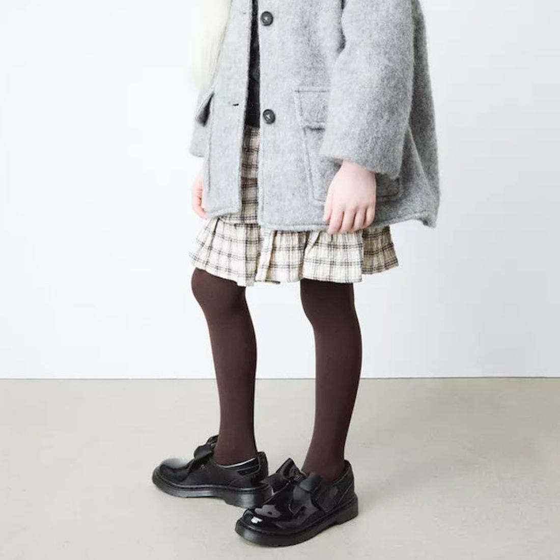 A child wearing a gray coat, plaid skirt, and Dr Martens Polley Patent black shoes with a wide ribbon bow on a white background.,
190665761818,
190665761832,
190665761856,
190665761863,
190665761764,
190665761788,
190665761801,, 190665761818, 190665761832