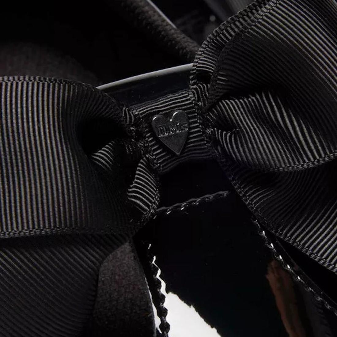 Close-up of a bow on the Dr Martens Polley T Bar black shoe with a large bow and a visible brand logo.,
190665761818,
190665761832,
190665761856,
190665761863,
190665761764,
190665761788,
190665761801,, 190665761818, 190665761832, 190665761856, 1906657618