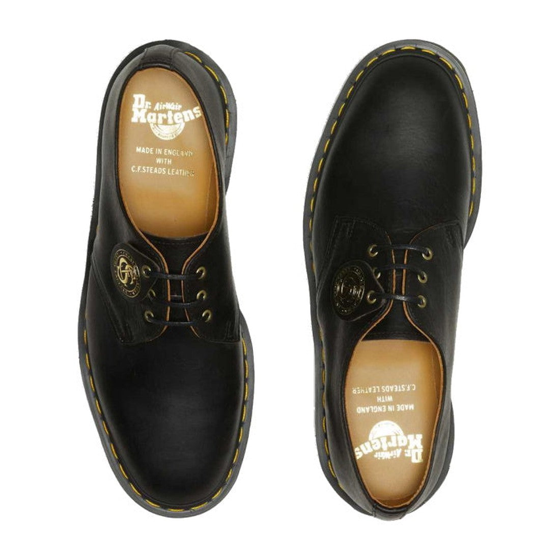 A pair of Dr Martens Made In England Oil Leather 1461 3 Eye Shoes, black with yellow-stitched soles, brown insoles with white branding, and a gold tag on one lace—classic vintage style viewed from above., 190665425826, 190665425895, 22989, 22986, 19066542