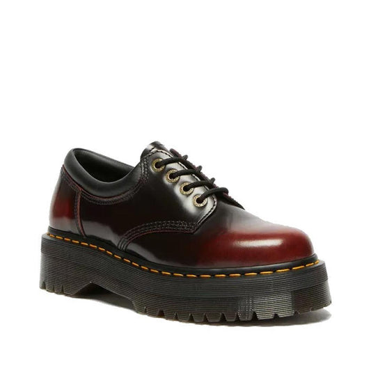 The Dr Martens 8053 Quad 4 Eye Shoe in Cherry Red Arcadia leather features a thick black ridged Goodyear welted platform sole with yellow stitching, displayed against a white background.