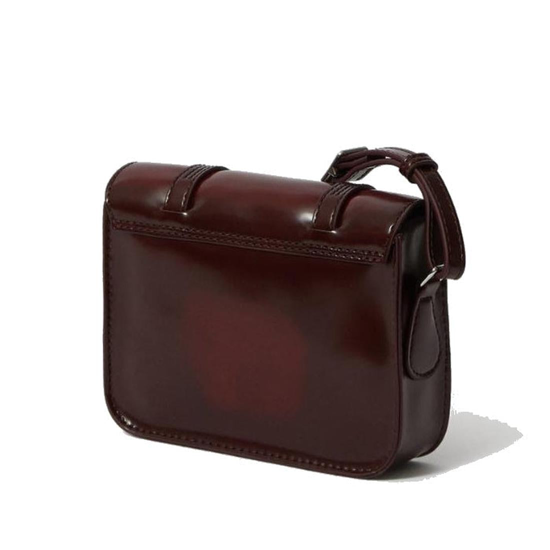 The Dr Martens 7 Inch Satchel Vegan Cherry Red Oxford Brush is a small, rectangular, glossy cherry red non-leather bag with a simple design and adjustable strap, perfect for everyday use, shown against a white background., 190665192087