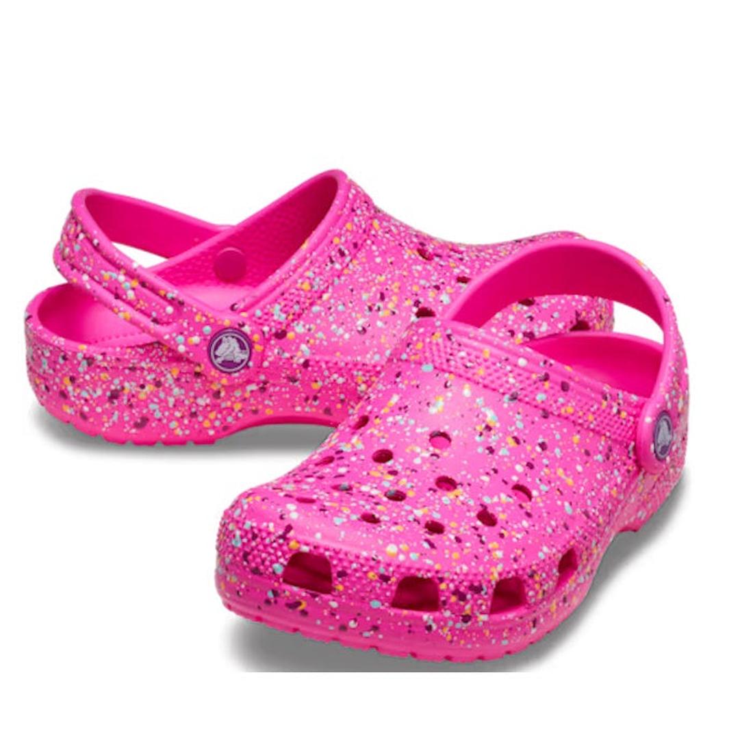 The Crocs Kids Toddlers Classic Clog K Paint Splatter Print in Bright Pink Multi features ventilation holes, an adjustable heel strap, and a fun multicolored glitter look—perfect lightweight shoes to add flair to your toddler’s outfit.