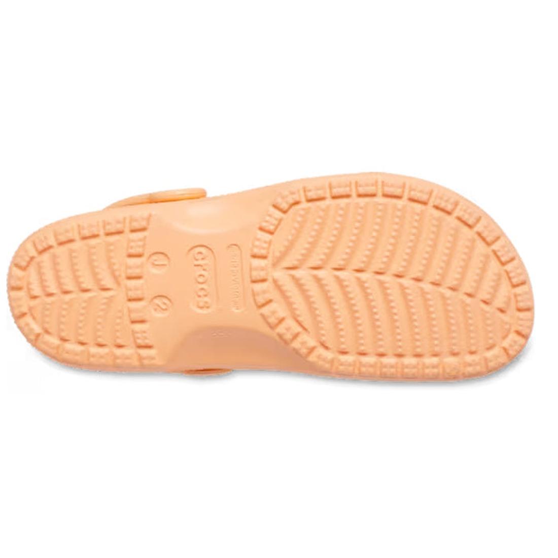 The image shows the sole of the Crocs Kids - Classic Clog Sunstone Soft Orange in Junior Youths Sizes, featuring a textured tread for grip and an embossed Crocs logo. This water-friendly design is ideal for active kids., 198445270154, 198445270161, 198445