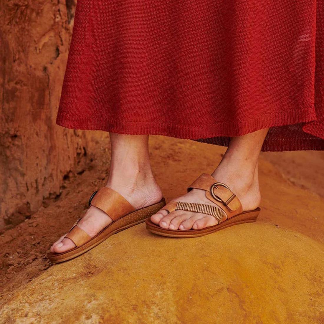 Los Cabos Bria Brandy on feet showing the right foot top view of teh sandal with the toe prong, cross strap with faux woven bamboo and the buckle adjustable strap over the top of the foot. Shows the left foot inside view of  toe prong and over the top of 