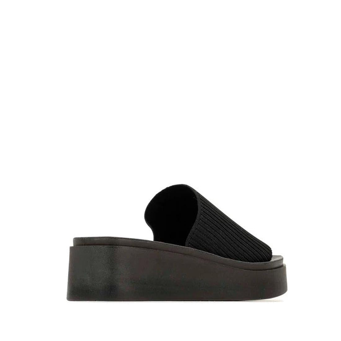 The Los Cabos Pass Women's Wedge Heeled Slide Sandal in black features a ribbed, closed-toe vegan leather upper and a thick, gently curved wedge sole, displayed in side profile on a plain white background., 9321191228464, 9321191228471, 9321191228488, 932