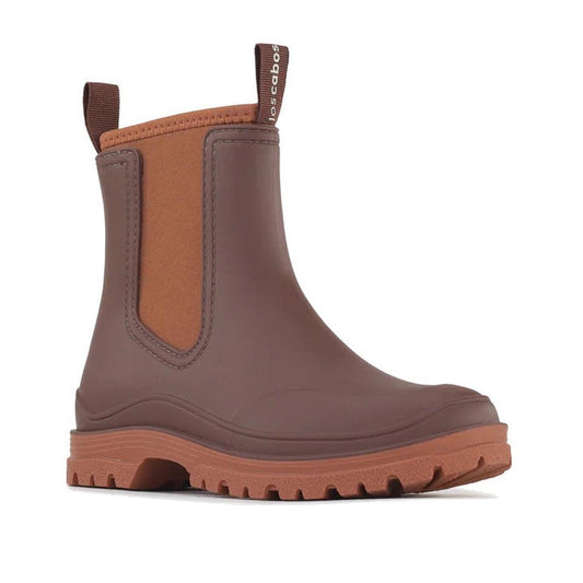 The Los Cabos Amelia Chocolate Ankle Rain Boot Waterproof features a brown, ankle-height design with textured sole, elastic side panels, neoprene lining, and front/back pull tabs for chic comfort in wet outdoor conditions.