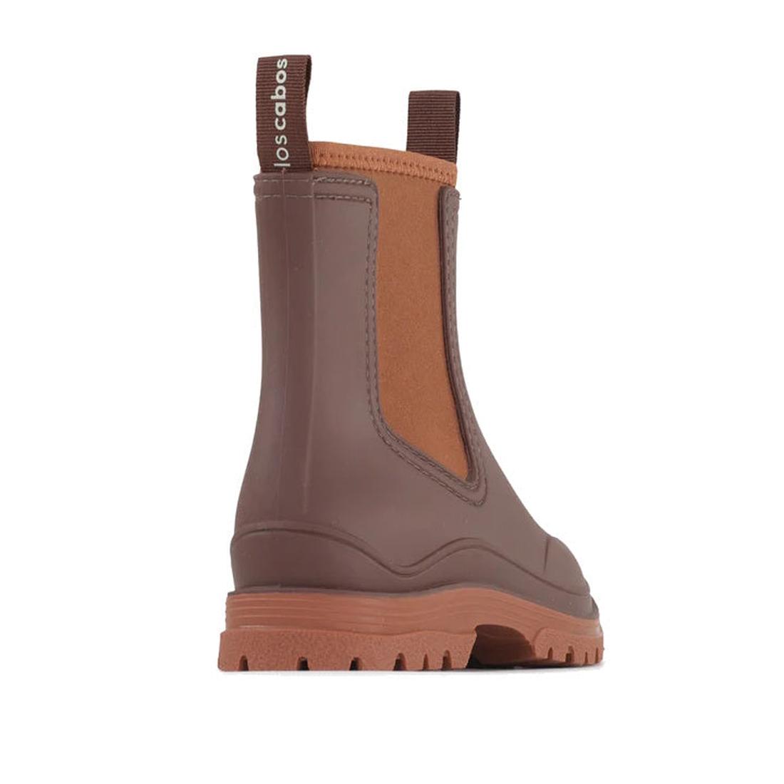 The Los Cabos Amelia Chocolate Ankle Rain Boot Waterproof features a chic brown ankle-length design, tan elastic side panel, comfy neoprene lining, back pull tab with "los cabos" label, and a thick treaded sole. Boot is angled to display the side and back