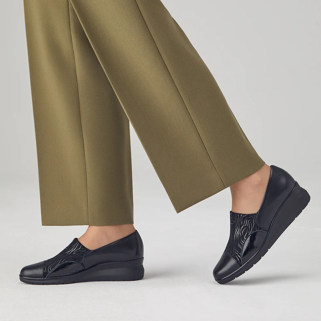 A person wears comfy olive green trousers and our Pitillos Womens Lycra and Patent Leather Shoe 10731—black wedges with easy slip-on fit.  ksnz, 8445191655554, 8445191655561, 8445191655578, 8445191655585