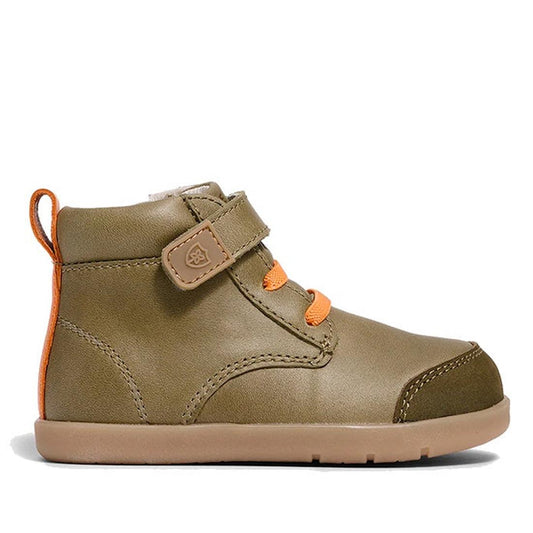 The Pretty Brave Jessie First Walker Hi Top Leather Olive Green is a genuine leather toddler sneaker in olive green with orange laces, velcro strap, and an orange heel pull tab, shown in side profile on a white background.