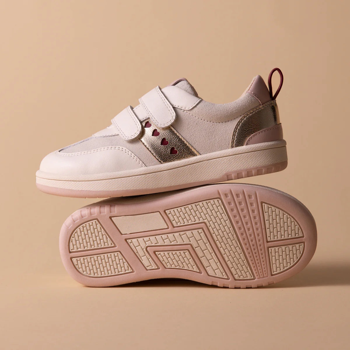 Two Pretty Brave River Hearts Leather Trainer sneakers in Pink Off White are shown. One stands upright, the other lies on its side to reveal the textured sole. Both feature light pink leather and velcro straps on a beige background., 9420075363854, 942007
