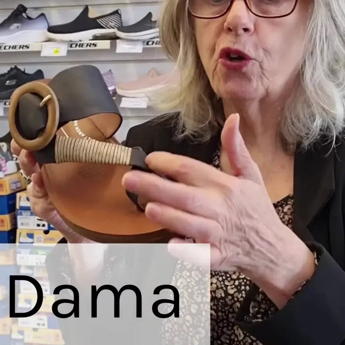 A friendly woman with glasses displays the Los Cabos Damas Black Light sandal, a comfy black thong jandal with cross-over straps and buckle.  ksnz