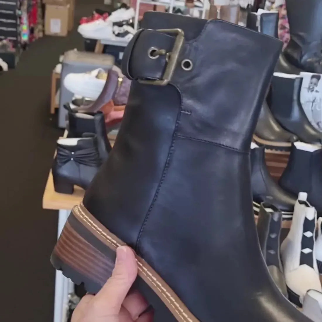 A parent holds the EOS Lineman Black Womens Leather Boot, a sturdy black combat boot with leather upper, side buckle, and chunky sole.  ksnz, 45055, 45049, 45050, 45051, 45052, 45053, 45054
