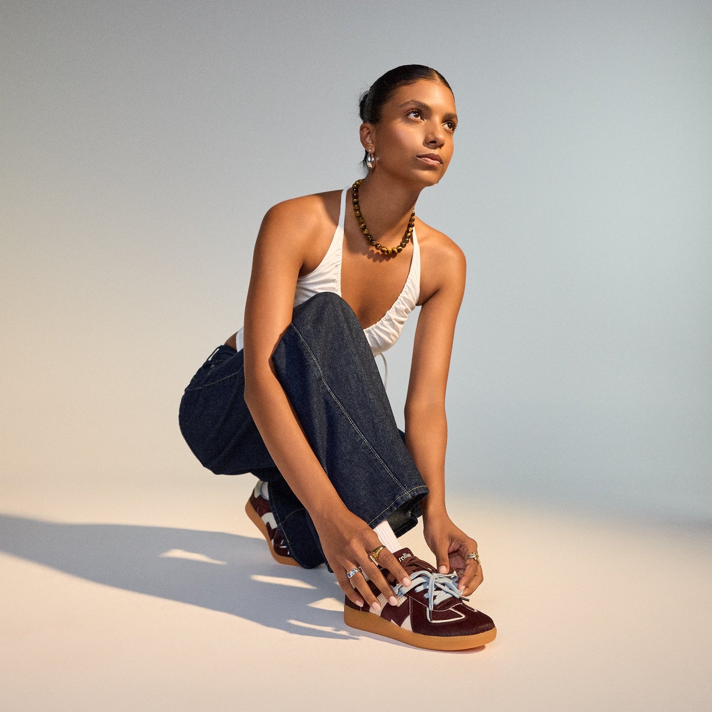 A mom ties the lace-up Rollie Womens Pace Dark Cherry Bone Suede Sneakers, featuring soft suede, white soles, and comfy cushioning.  ksnz, 9339554000315, 9339554000317, 9339554000164, 9339554000056, 9339554000182