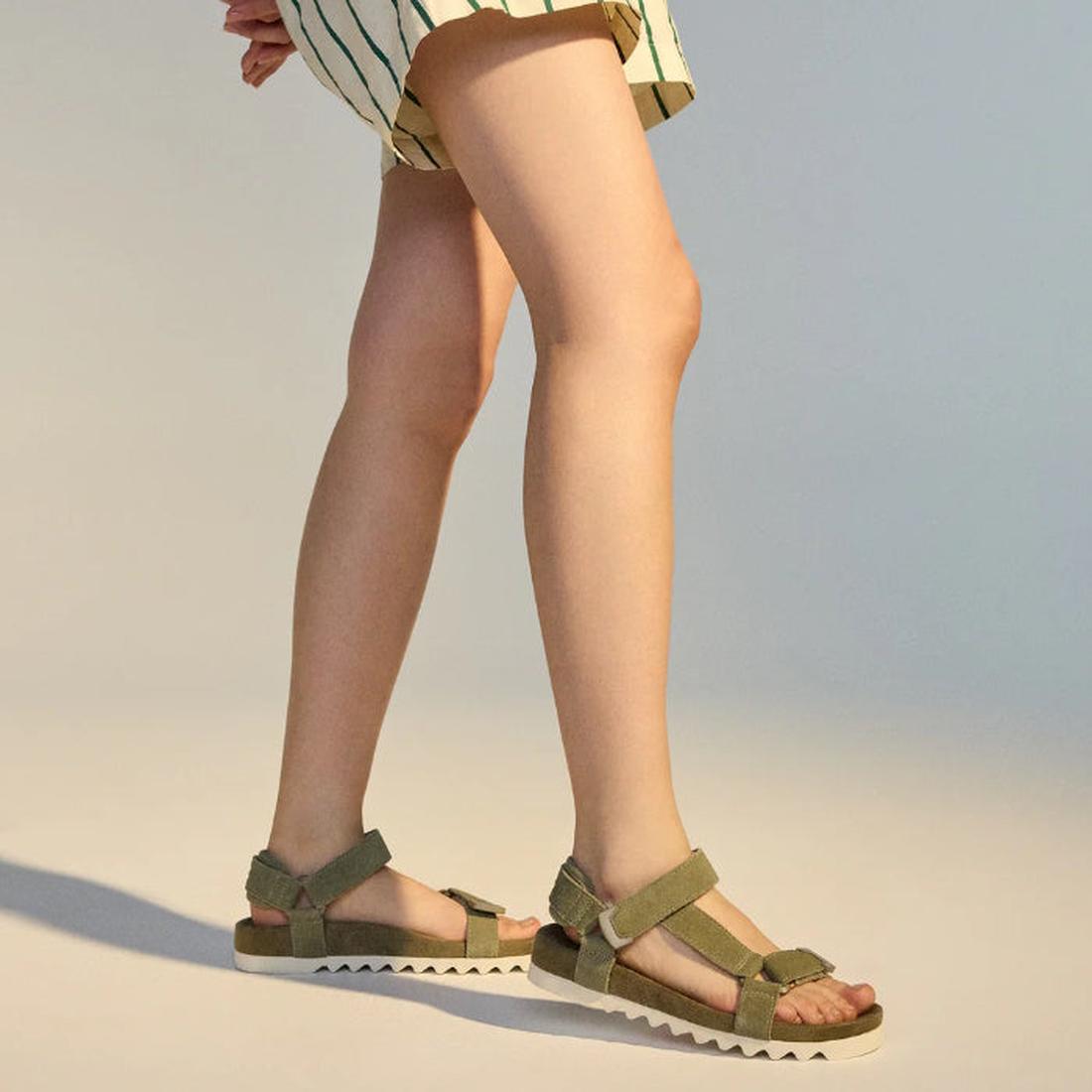 A person wears the Rollie Womens Sandal Tooth Wedge in Sage/White, featuring a unique EVA sawtooth wedge outsole, paired with a striped skirt and standing on a neutral background, with their legs in focus., 48171, 9781760793883, 9781760793890, 97817607939