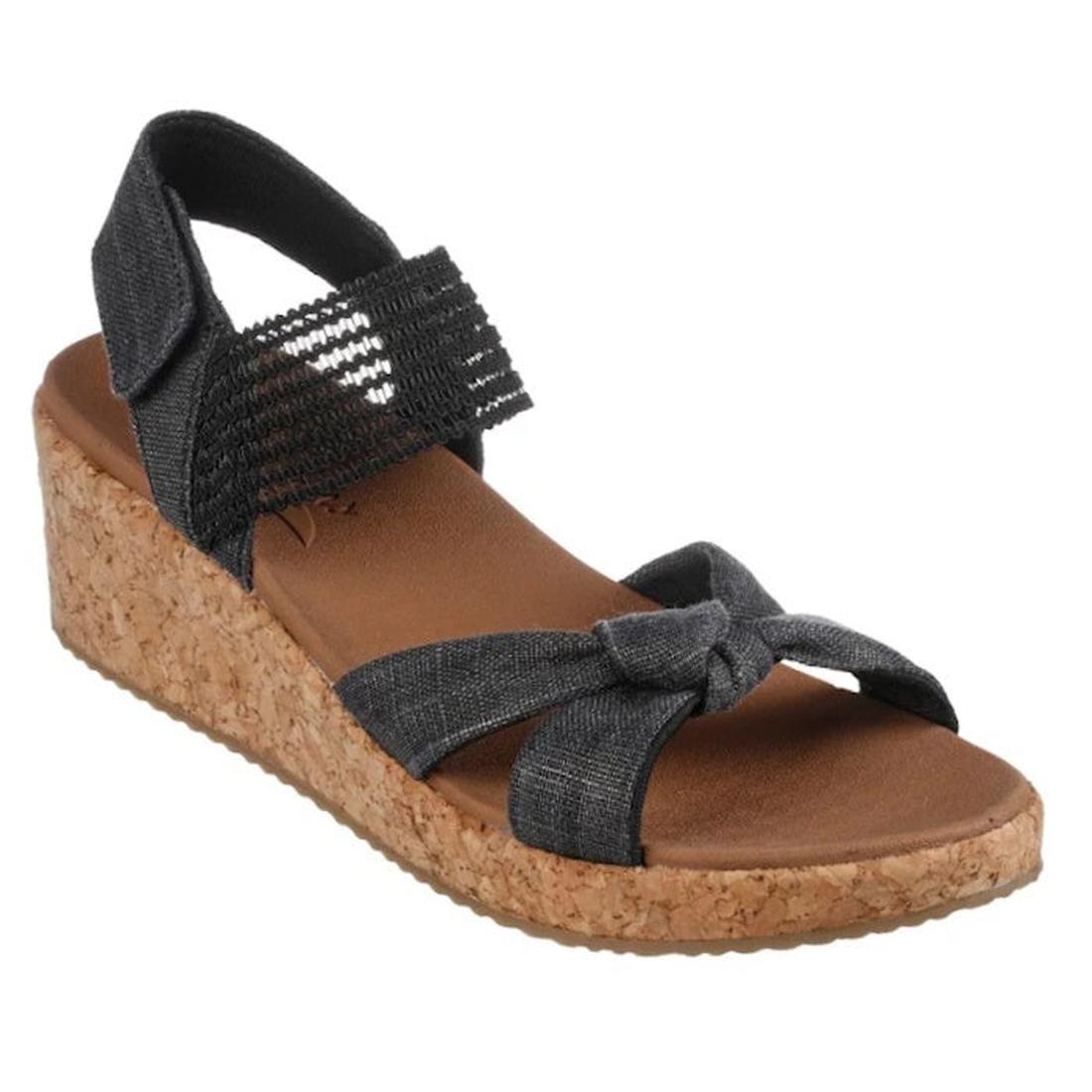 Skechers Women's Arch Fit Beverlee Juliet Wedge Sandal in black has a comfy cork sole, front knot, elastic ankle strap, and open toe.  ksnz