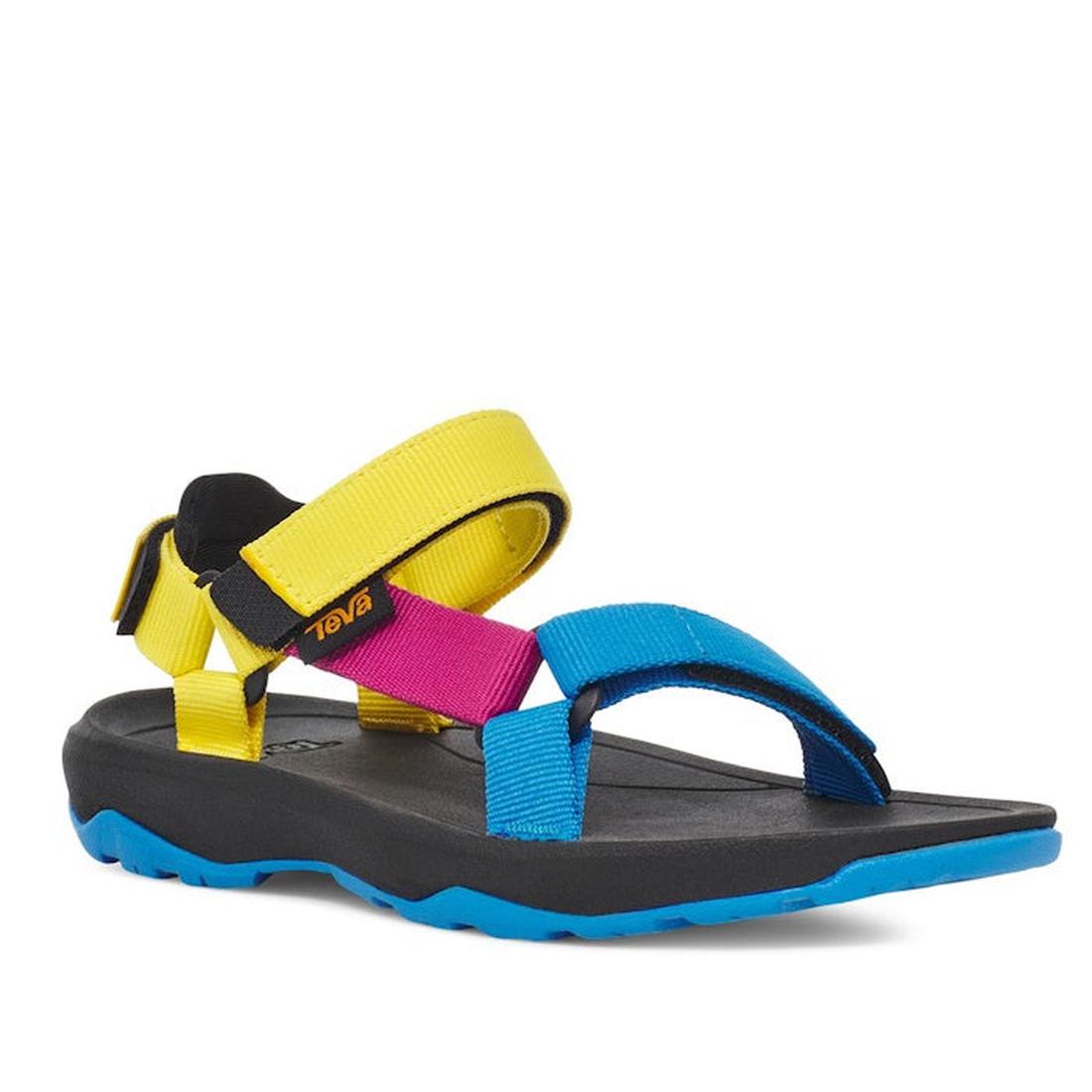 The Teva Kids - K Hurricane XLT2 Water Multi sandal features a black sole, blue toe strap, pink and yellow ankle straps, and a blue outsole made from recycled polyester webbing, shown on a white background.