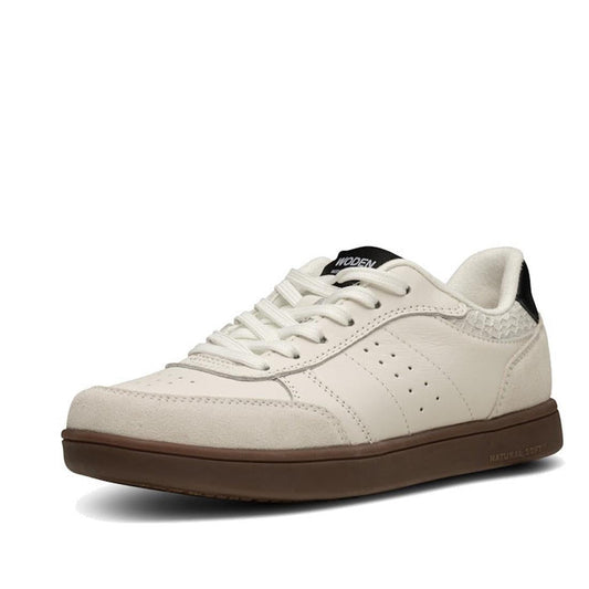 The Woden Bjork Mix Women's Leather Sneaker in Blanc de Blanc/Black features a brown rubber sole, perforated sides, white laces, a black heel accent, and is made with recycled polyester. Shown at an angle highlighting the outer side and front.