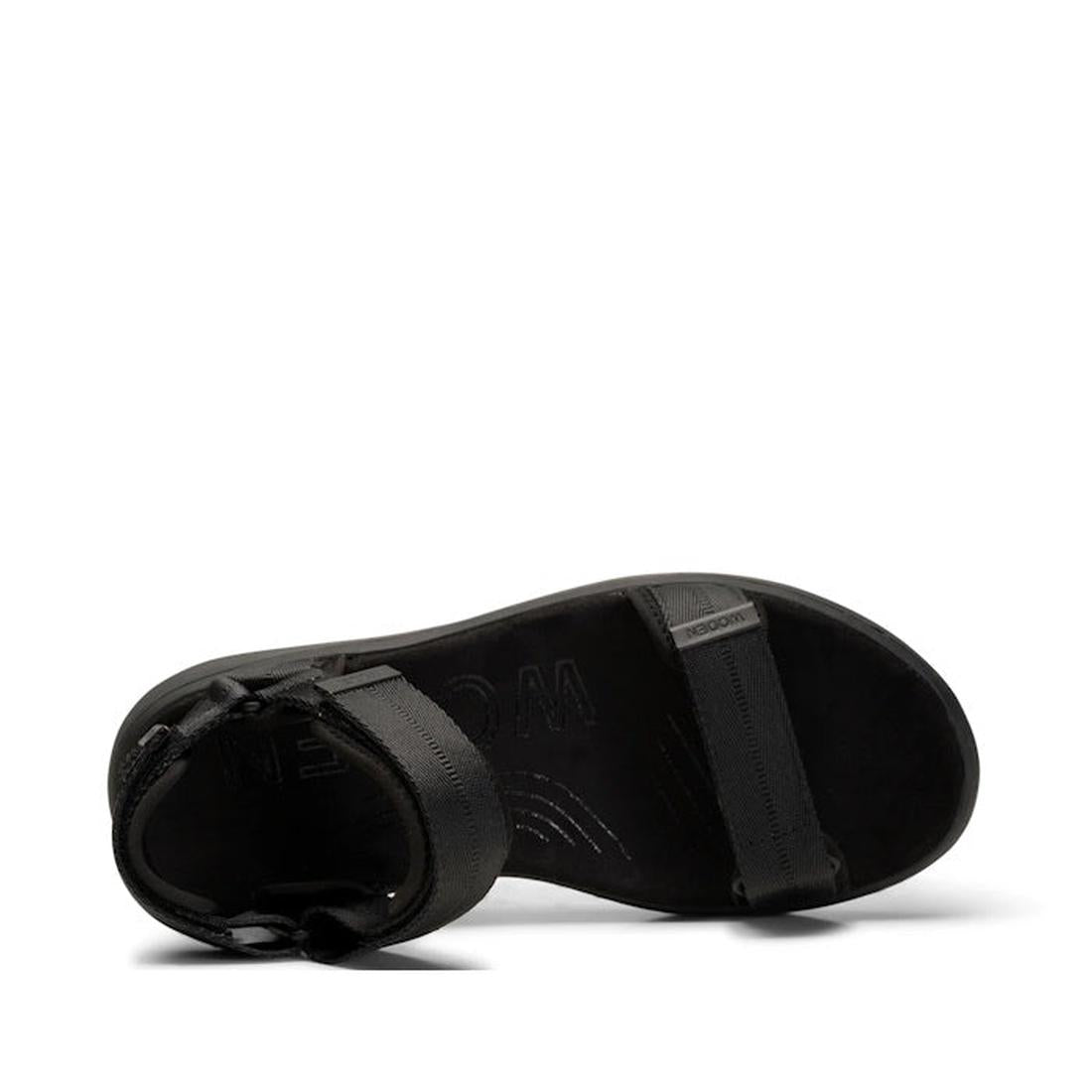 The Woden Line Women's 3 Strap Sandal Black is a minimalist, flat black sandal seen from above, with adjustable ankle buckle and toe strap. The brand is subtly embossed on the footbed for added style and comfort., 5713326456912, 5713326456929, 57133264569